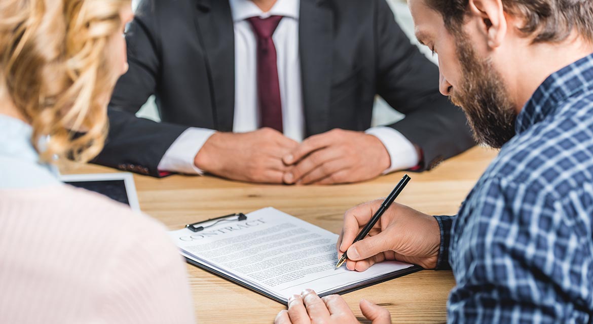 man signing contract at table